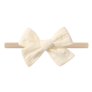 Detailed view of cream bow baby headband made of soft textured knit fabric
