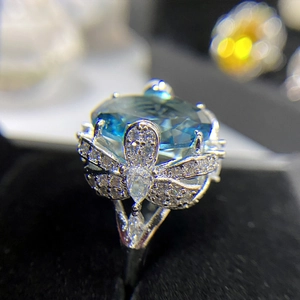 Detail of an oversized oval blue gemstone ring with intricate silver butterfly accents