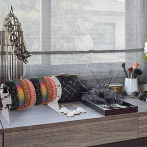 Clear acrylic cylinder stand organizing various colorful rhinestone hair ties on a wooden table