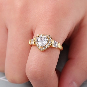 Macro di un anello halo dorato con zircone a cuore e pietre laterali a taglio baguette