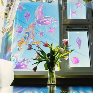 Rainbow mermaid tail window clings reflecting colorful light with indoor tulips
