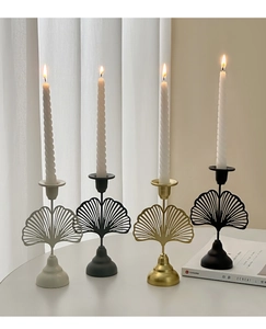 Detailed view of metal ginkgo leaf candle holders in four elegant finishes on a table