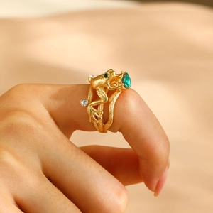 Close-up of golden frog ring with pear-cut green gemstone and sparkling diamond accents