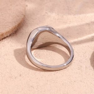 Macro close-up of a polished stainless steel polar star signet ring on textured beige surface