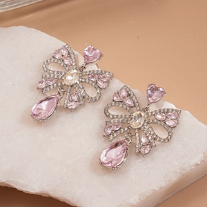 Gros plan détaillé de boucles d'oreilles nœud avec cristal rose en forme de goutte