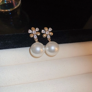 Detail of gold flower earrings with sparkling zircons and elegant hanging white pearls
