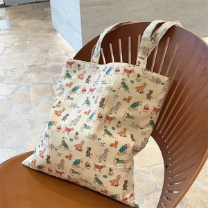 Close-up of cream canvas tote bag with colorful dog prints resting on a vintage chair