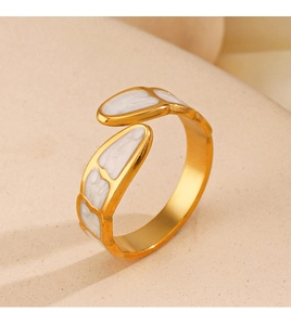 Macro detail of 18K gold plated snake ring with white enamel inlay on beige texture