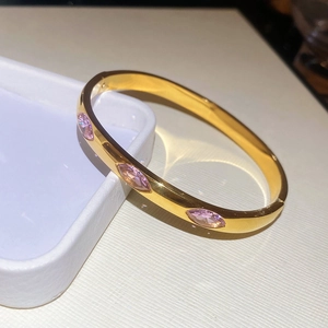 Detail of gold-plated bangle with marquise-cut pink cubic zirconia on white display box