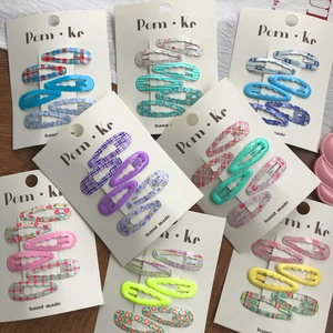Flat lay of colorful wave-shaped metal hair clips with floral and plaid patterns