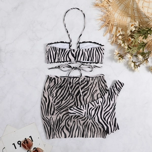 Flat lay of zebra print bikini set with matching mesh skirt on marble surface