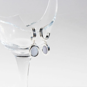 Orecchini in argento con pietra naturale blu appesi sul bordo di un vetro