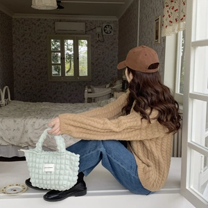 Detail of mint green waffle texture handbag with LOVE SOZAKKA label in a cozy home setting