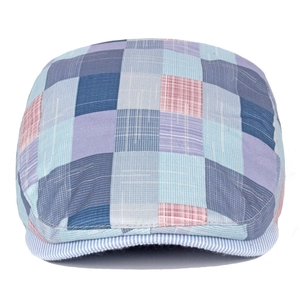 Detail of colorful patchwork newsboy cap featuring multi-colored plaid and stripe textures