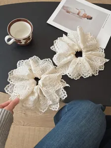 Close-up of beige lace scrunchies with intricate floral embroidery and scalloped edges