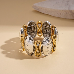 Macro detail of elastic bracelet with hammered metal texture and gold infinity accents