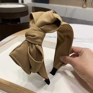 Detailed view of a khaki fabric headband featuring a large multilayered bow design