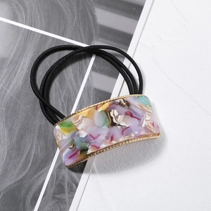 Detail of square acetate hair tie with colorful marble patterns and gold metal trim