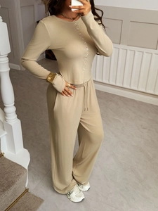 Close-up of beige ribbed knit texture on long sleeve button-up shirt and drawstring pants