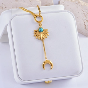 Detail of gold Y-necklace with turquoise sunburst and crescent moon pendant charms