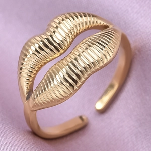 Detailed macro view of adjustable golden lip-shaped ring with fine textured finish
