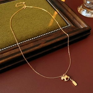 Vintage style gold-plated pony and coin pendant necklace on rustic wooden decor