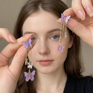Detailed macro of purple acrylic butterfly tassel earrings with gold-tone metal chains