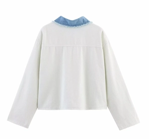 Detail view of a long-sleeve jacket showing white fabric with blue denim collar stitching