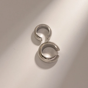 Macro detail of silver C-shaped stainless steel ear cuffs with a polished metallic finish