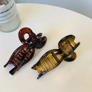 Detail of amber and tortoiseshell resin shark hair clips on a clean white surface