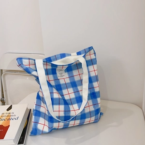 Detail of blue and white checkered canvas tote bag with thick white cotton shoulder straps