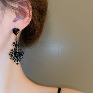 Close-up of gothic black heart earrings with rhinestones worn on the model's ear