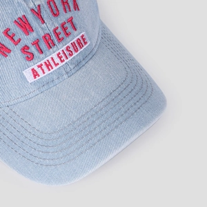 Close-up of red 3D embroidery and washed denim texture on a vintage baseball cap