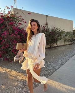 Outdoor shot of white pleated dress with drawstring neckline and straw clutch bag