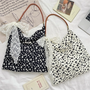 Détail du sac cabas en toile fleurie avec nœud en dentelle blanche et bandoulière