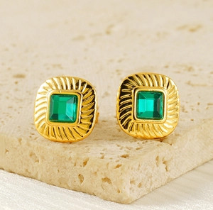 Macro view of vintage gold stud earrings with green square zircon and spiral texture