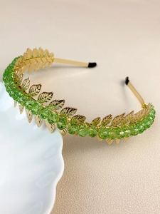 Detail of handmade golden leaf headband with green crystal beads for elegant women hair