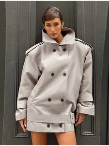 Detailed view of light gray double-breasted trench coat with epaulettes and wide hem belt