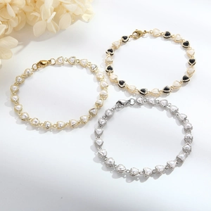 Detailed view of heart charm bracelets in gold and silver finishes with pearl accents