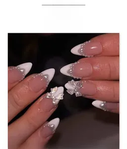 Macro detail of almond nails with pearl edges and silver 3D butterfly ornaments