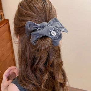 Detail of dark grey paisley bow hair tie with BOTANI tag on brunette wavy hair