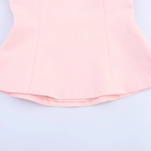 Detailed close-up showing the hem stitching and pink polyester fabric of the halter top