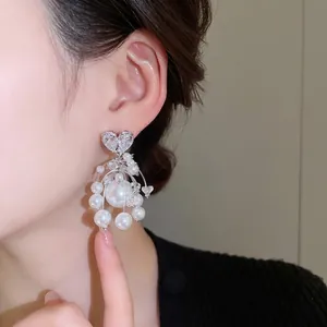 Orecchini pendenti in argento con zircone a cuore e perle bianche indossati