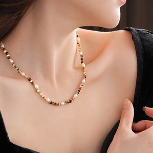 Dettaglio di una collana con perle d'acqua dolce e occhio di tigre sul collo