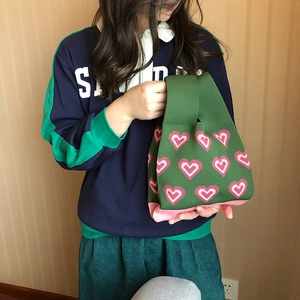 Detail shot of the knit tote bag texture with pink heart patterns on green fabric