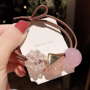 Detail of pink crystal beads and golden triangle charms on a brown elastic hair tie