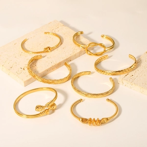 Collection of 18K gold plated stainless steel knot and braided bangles on stone tray