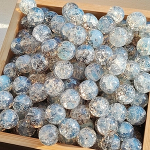 Blue gold-dusted glass beads with cracked texture in a wooden tray for DIY jewelry