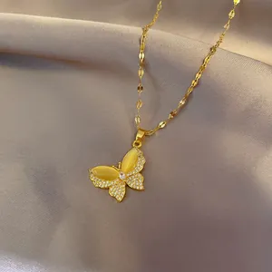 Detailed close-up of golden butterfly pendant with cat-eye stone and white zircons on silk