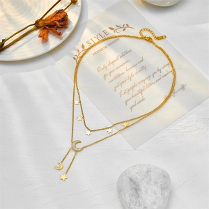 Double-layered gold star and moon necklace with white shell inlay on a layered chain